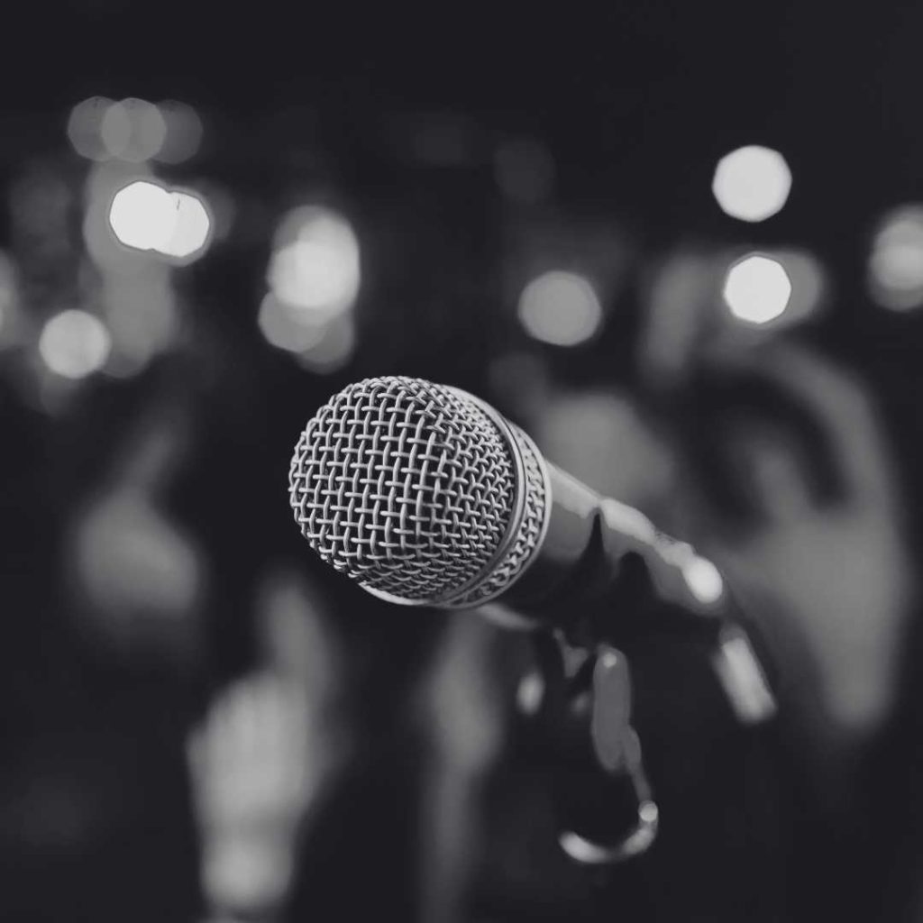 Black and white photo of a microphone with blurred lights in the background